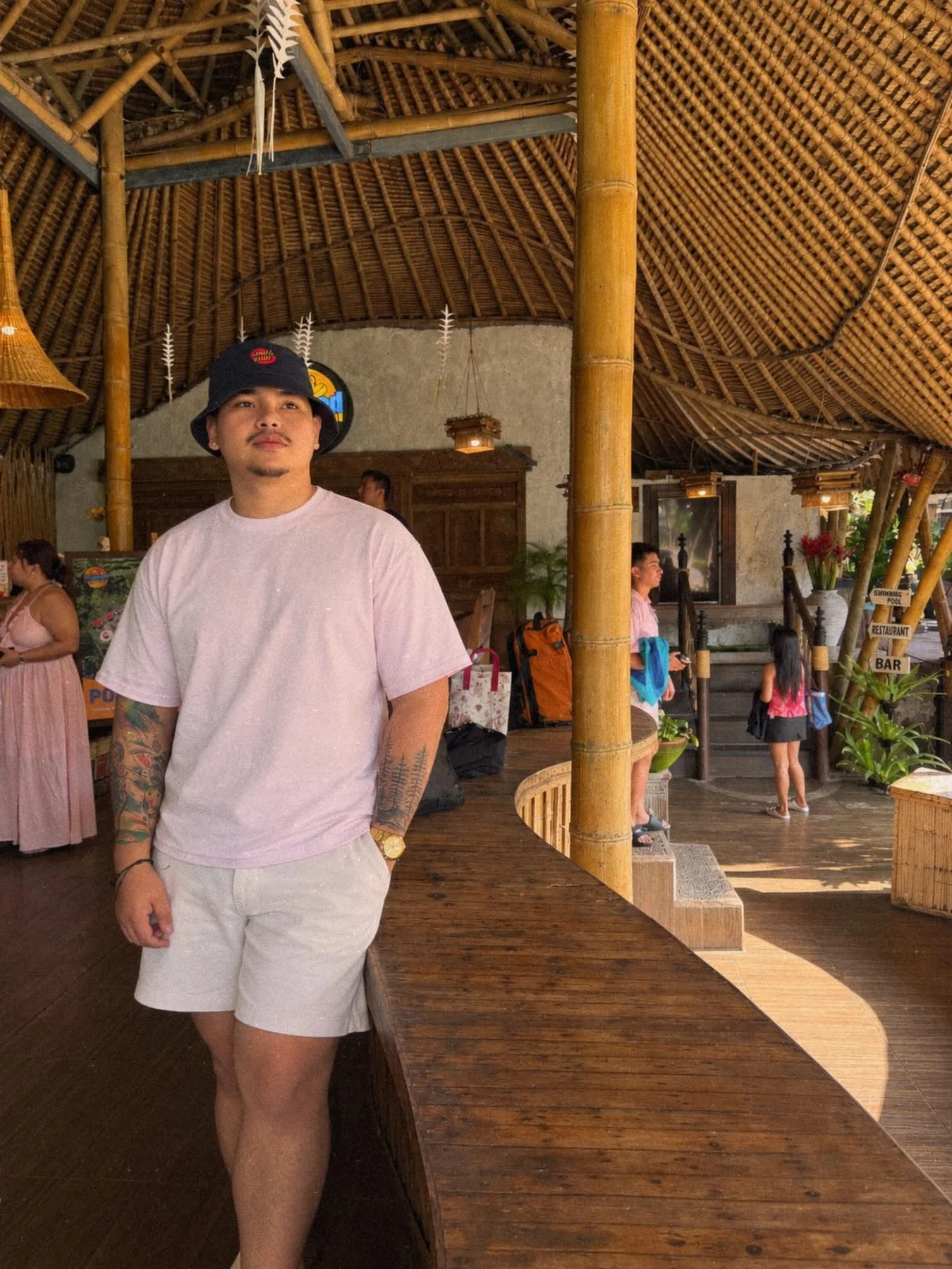 Ean in a pink shirt beneath a bamboo pavilion