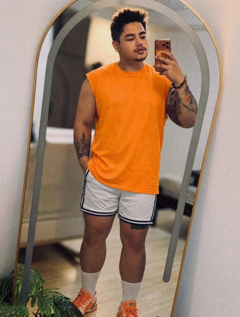 Ean wearing an orange shirt in a mirror portrait